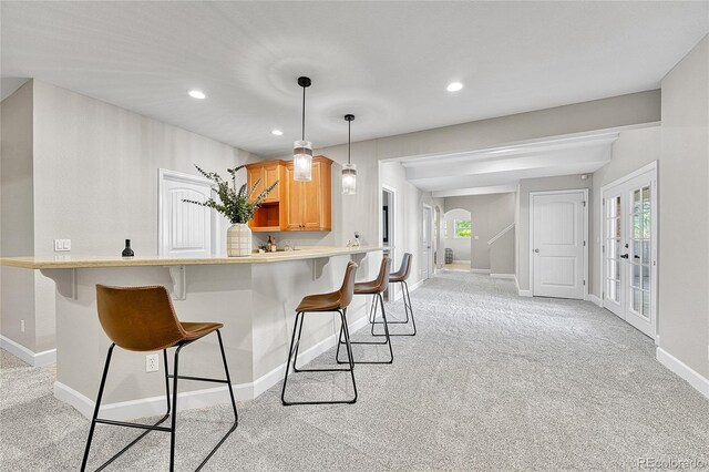 kitchen with a kitchen bar, baseboards, light colored carpet, and recessed lighting