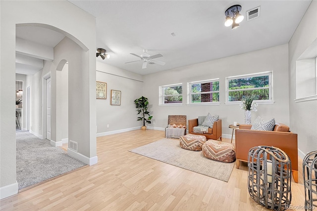 sitting room featuring arched walkways, a ceiling fan, wood finished floors, and baseboards