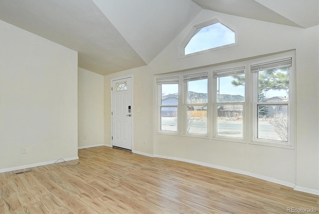 entryway featuring a mountain view, plenty of natural light, light hardwood / wood-style floors, and vaulted ceiling