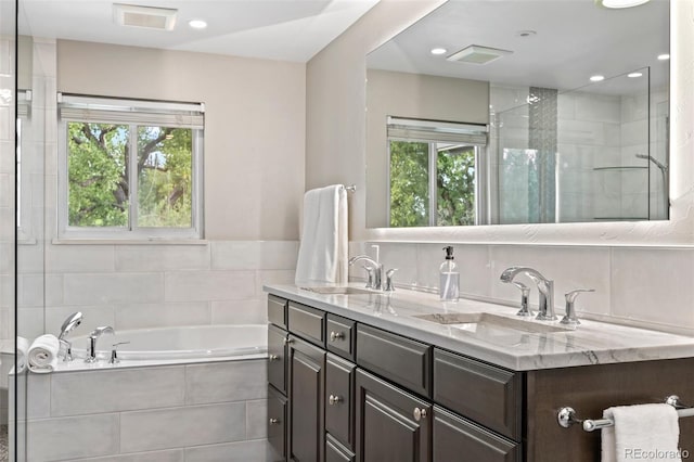 bathroom featuring vanity, backsplash, a healthy amount of sunlight, and plus walk in shower