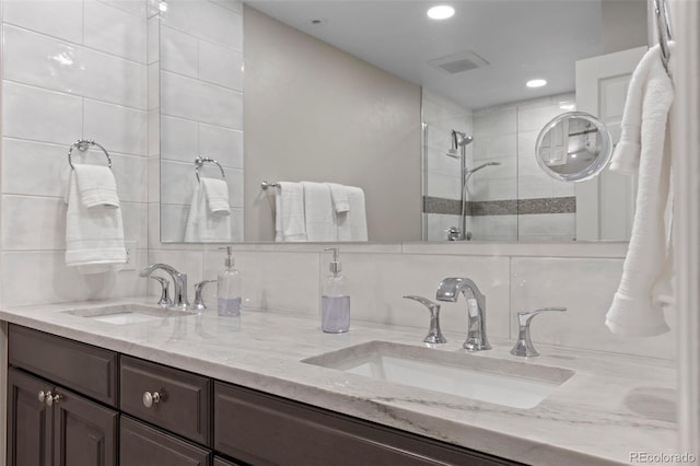 bathroom with vanity, backsplash, and tiled shower