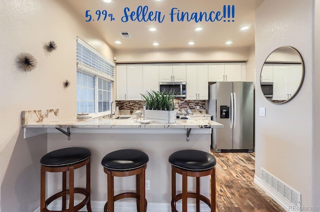 kitchen with stainless steel appliances, tasteful backsplash, white cabinets, and kitchen peninsula