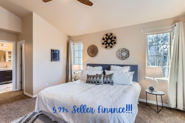 carpeted bedroom featuring ceiling fan, vaulted ceiling, sink, and ensuite bath