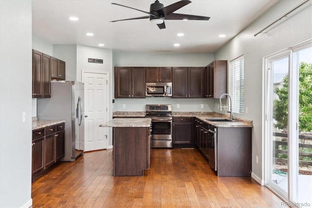 5021 S Rome St, Aurora, CO 80015 - kitchen with stainless steel appliances, a sink, a center island, a ceiling fan, and dark wood-style flooring