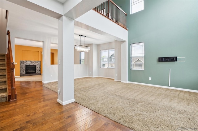 5021 S Rome St, Aurora, CO 80015 - unfurnished living room featuring stairs, baseboards, a stone fireplace, wood-type flooring, and a chandelier