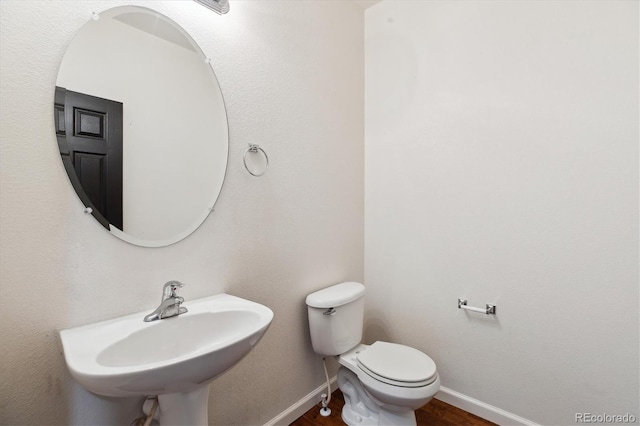 5021 S Rome St, Aurora, CO 80015 - half bath with baseboards, wood finished floors, toilet, and a sink