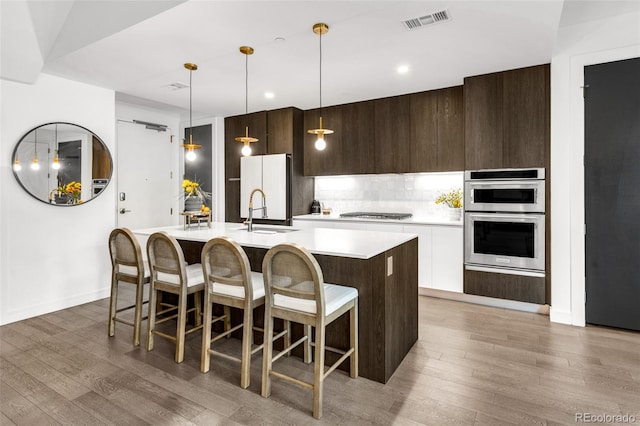 kitchen featuring an island with sink, a kitchen breakfast bar, wood-type flooring, and white cabinets