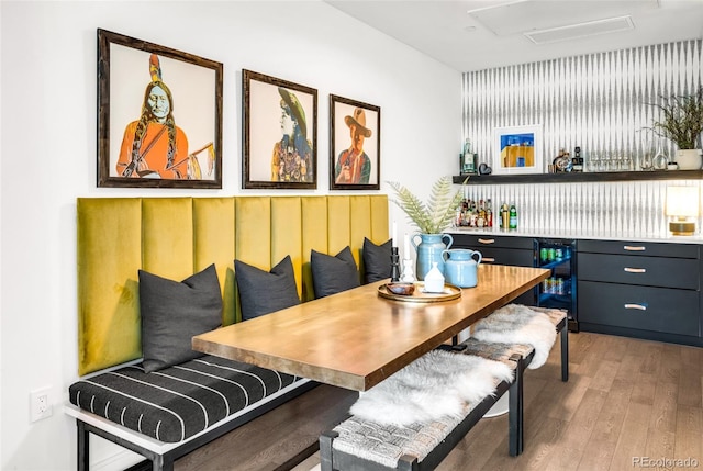 dining room featuring hardwood / wood-style floors, wine cooler, and bar