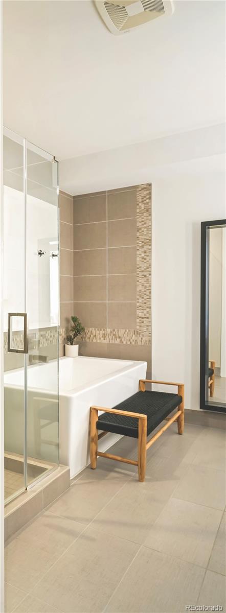 bathroom with tile walls, an enclosed shower, and tile patterned floors