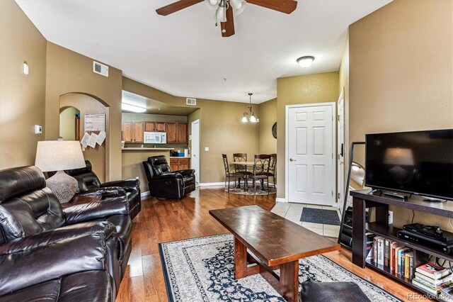 living room featuring wood-type flooring and ceiling fan with notable chandelier