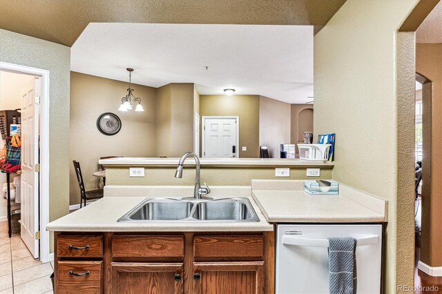 kitchen featuring white dishwasher, hanging light fixtures, light tile patterned floors, sink, and an inviting chandelier