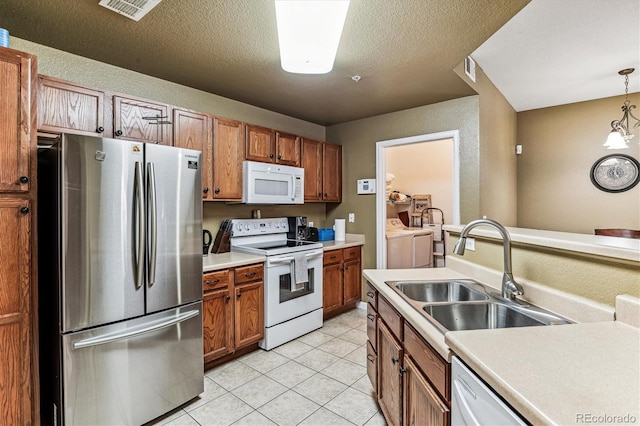 kitchen featuring white appliances, light tile patterned floors, sink, pendant lighting, and independent washer and dryer