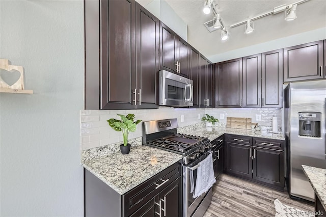 12910 Grant Cir W Unit C, Thornton, CO 80241 - kitchen featuring appliances with stainless steel finishes, backsplash, light stone counters, and light wood-style flooring
