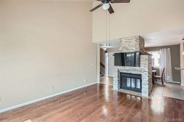 unfurnished living room with wood-type flooring, ceiling fan, and a fireplace