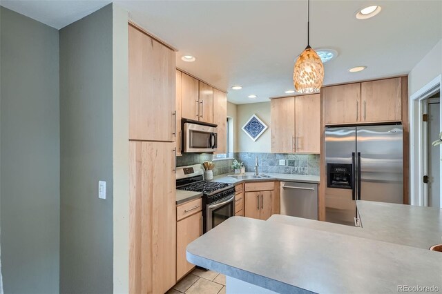 kitchen featuring light brown cabinetry, stainless steel appliances, hanging light fixtures, and kitchen peninsula