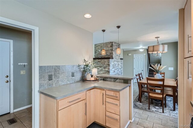 kitchen with pendant lighting, decorative backsplash, kitchen peninsula, and light brown cabinetry