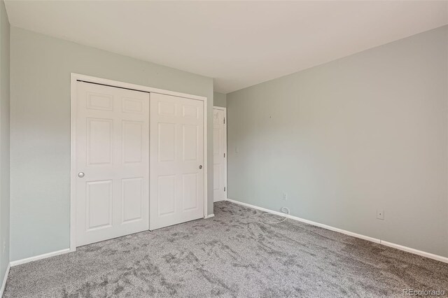 unfurnished bedroom with light carpet and a closet