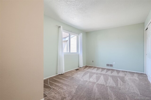 carpeted spare room featuring a textured ceiling