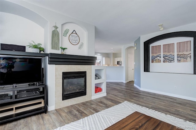 living room with a tiled fireplace and hardwood / wood-style floors