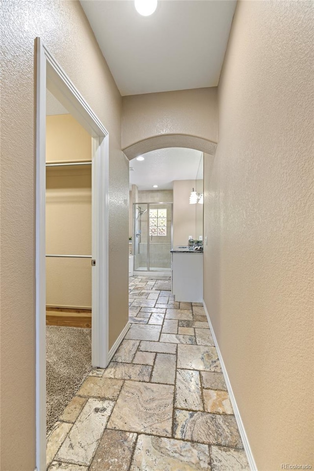 6405 Eagle Feather Trl, Littleton, CO 80125 - hallway with stone tile flooring, arched walkways, a textured wall, and baseboards