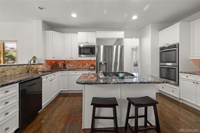 6405 Eagle Feather Trl, Littleton, CO 80125 - kitchen with stainless steel appliances, a sink, a breakfast bar, dark wood-style flooring, and white cabinets