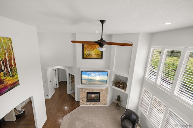 6405 Eagle Feather Trl, Littleton, CO 80125 - unfurnished living room featuring a glass covered fireplace, wood finished floors, arched walkways, recessed lighting, and ceiling fan