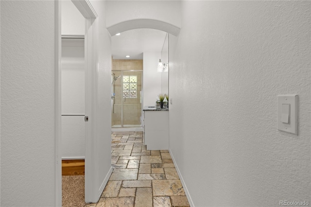 6405 Eagle Feather Trl, Littleton, CO 80125 - hall featuring stone tile flooring, arched walkways, baseboards, recessed lighting, and a textured wall