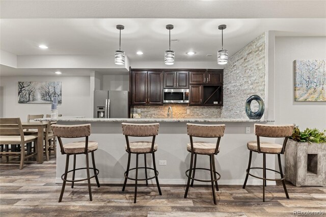6405 Eagle Feather Trl, Littleton, CO 80125 - kitchen with stainless steel appliances, dark brown cabinetry, wood finished floors, recessed lighting, and tasteful backsplash