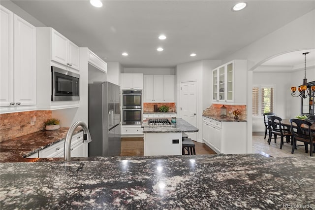 6405 Eagle Feather Trl, Littleton, CO 80125 - kitchen featuring appliances with stainless steel finishes, recessed lighting, a chandelier, arched walkways, and dark stone counters
