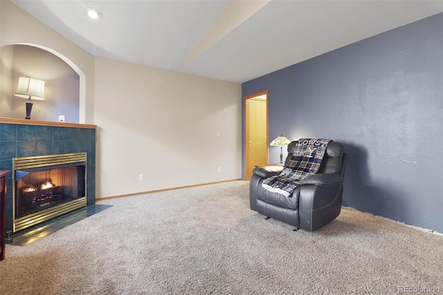 living area with a tiled fireplace, carpet, and lofted ceiling