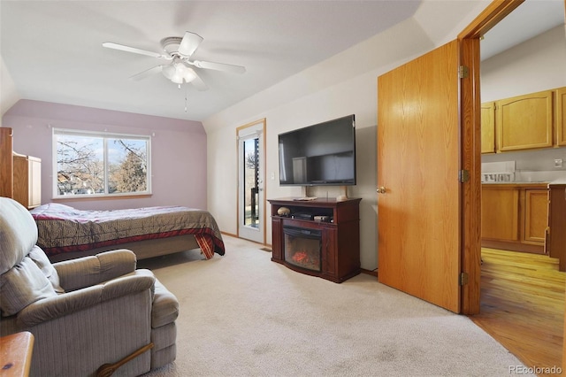 bedroom featuring a fireplace, light colored carpet, and ceiling fan