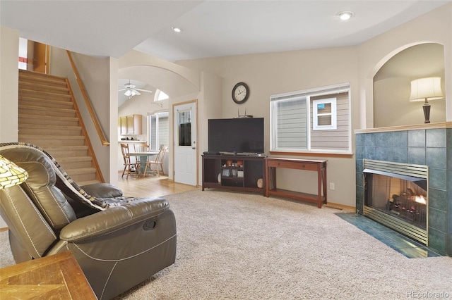 carpeted living room with a tile fireplace and ceiling fan