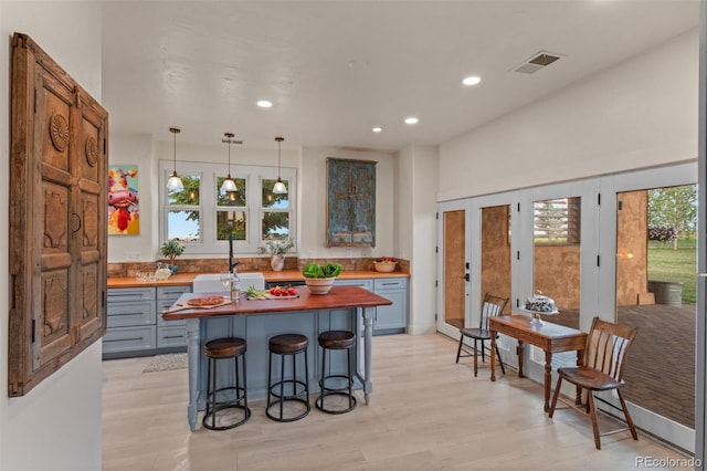 11881 County Road 37, Fort Lupton, CO 80621 - kitchen with butcher block countertops, recessed lighting, an island with sink, a kitchen breakfast bar, and light wood-style flooring