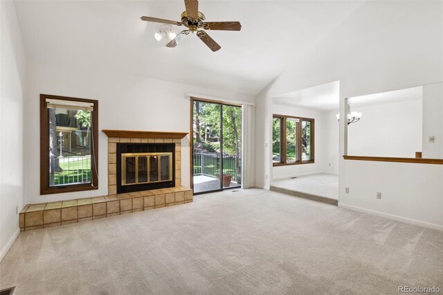 unfurnished living room featuring light colored carpet, ceiling fan with notable chandelier, a fireplace, and high vaulted ceiling