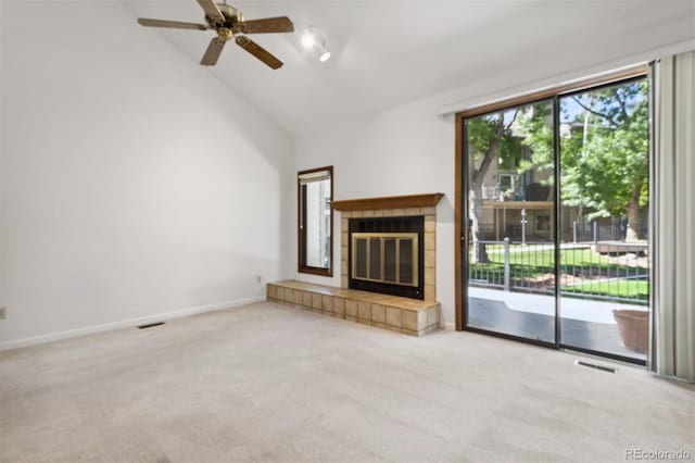 unfurnished living room with light carpet, a tiled fireplace, ceiling fan, and vaulted ceiling