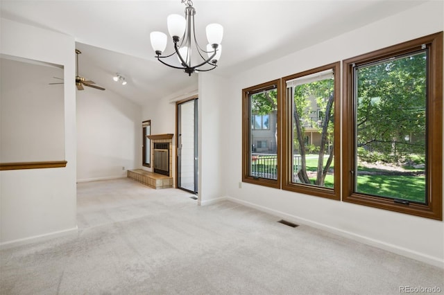 unfurnished living room featuring ceiling fan with notable chandelier, a tiled fireplace, light colored carpet, and vaulted ceiling