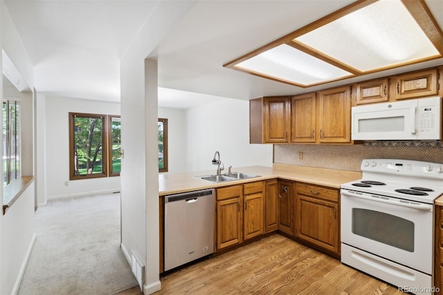 kitchen featuring light hardwood / wood-style floors, sink, kitchen peninsula, decorative backsplash, and white appliances