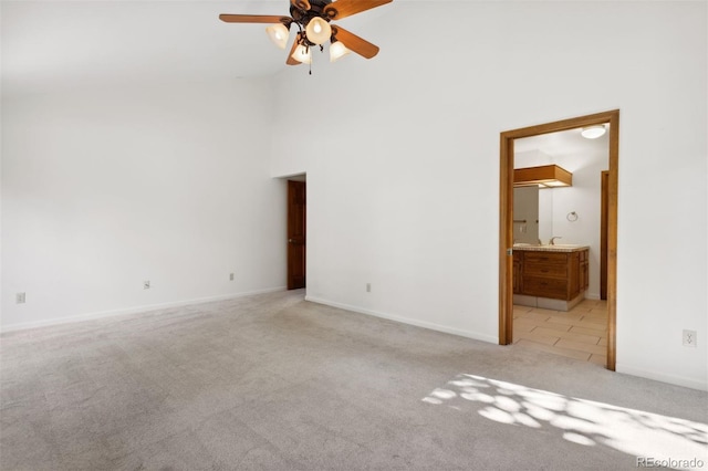 spare room featuring ceiling fan, light colored carpet, and high vaulted ceiling