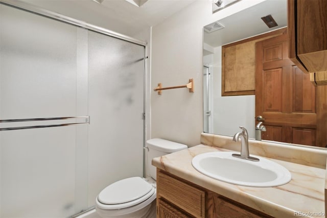 bathroom with vanity, toilet, and a shower with door