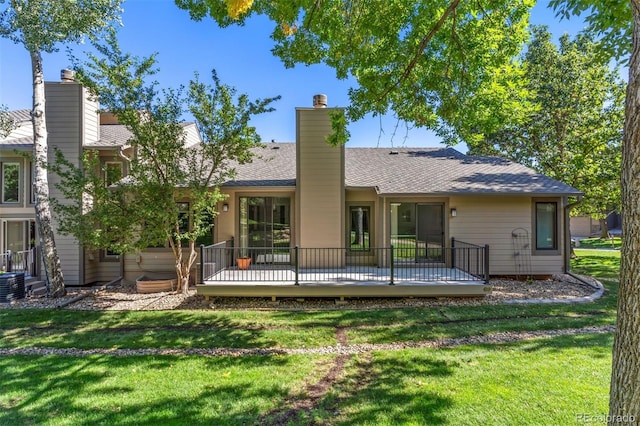 rear view of property featuring a lawn, a wooden deck, and cooling unit