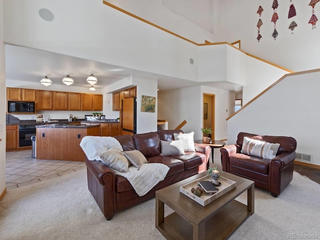 living area with light tile patterned floors, visible vents, a towering ceiling, and light carpet