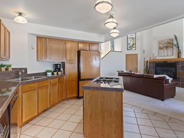 kitchen with light tile patterned floors, light colored carpet, stainless steel appliances, and a sink