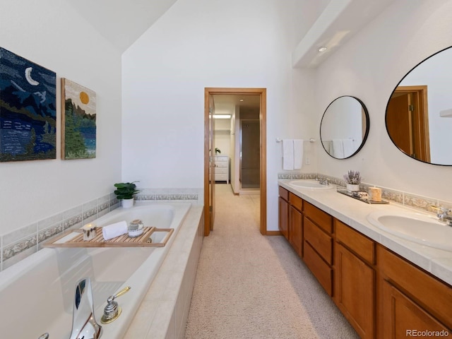 bathroom featuring vaulted ceiling, a garden tub, double vanity, and a sink