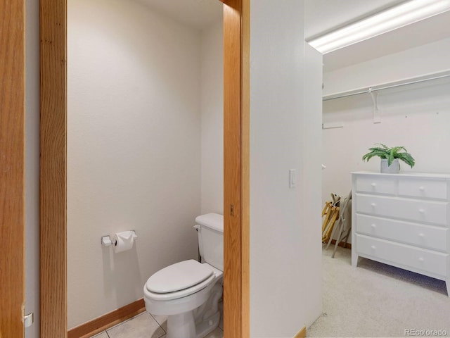 bathroom featuring baseboards, toilet, and tile patterned flooring