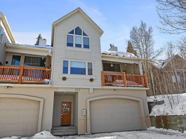 view of front of home with stucco siding, a balcony, an attached garage, and a chimney