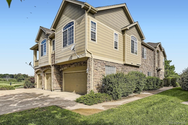 371 Granby Way Unit C, Aurora, CO 80011 - view of property exterior featuring stone siding, a garage, concrete driveway, and a yard