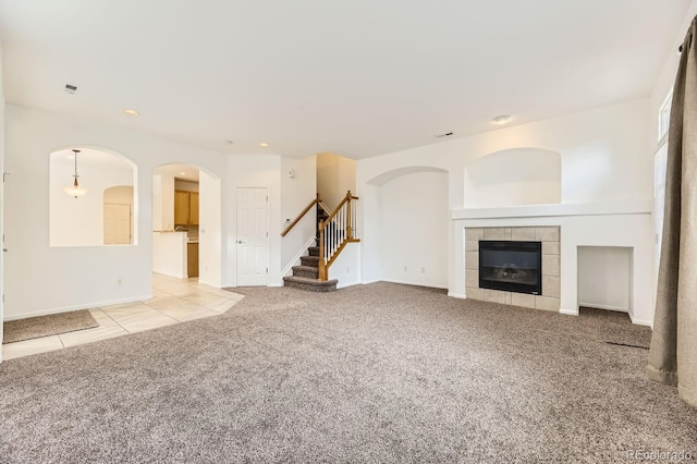 371 Granby Way Unit C, Aurora, CO 80011 - unfurnished living room featuring carpet, stairs, a tiled fireplace, tile patterned floors, and arched walkways