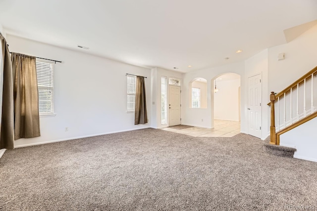 371 Granby Way Unit C, Aurora, CO 80011 - unfurnished living room featuring arched walkways, light colored carpet, healthy amount of natural light, stairs, and recessed lighting