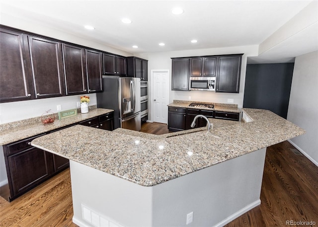 kitchen featuring a center island with sink, stainless steel appliances, sink, and dark wood-type flooring