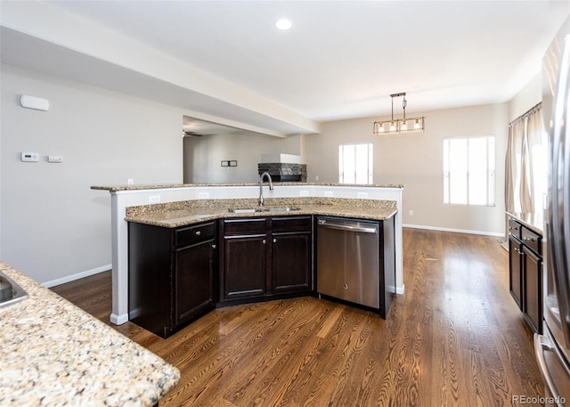 kitchen with dark wood-type flooring, an island with sink, decorative light fixtures, stainless steel dishwasher, and sink